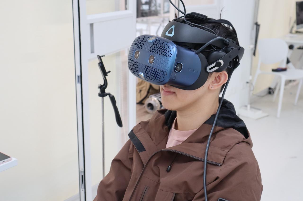 参与者侧面佩戴VR头显与腕部设备观看实验
