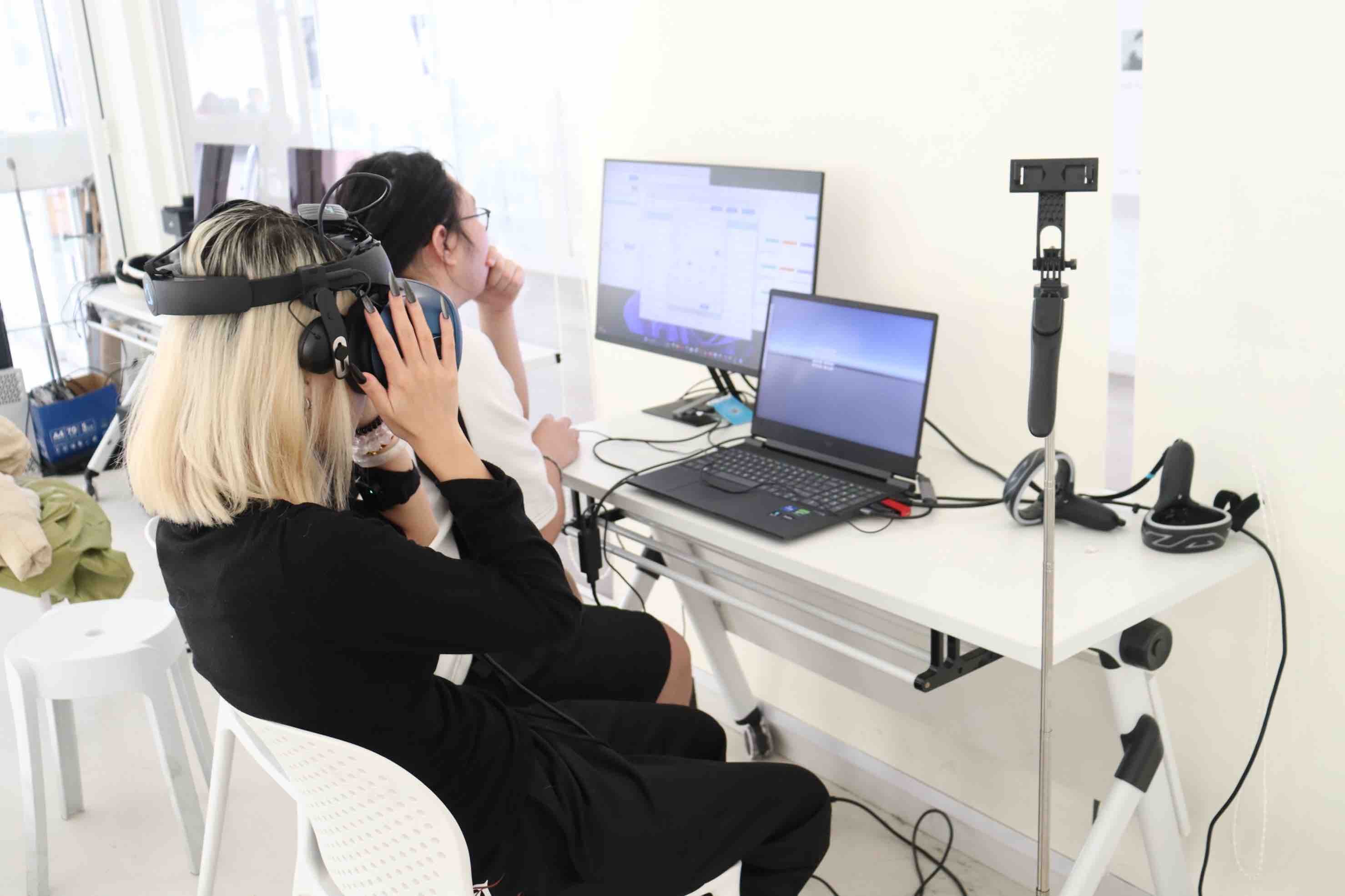 参与者与研究人员面对 VR 刺激和采集显示器进行实验